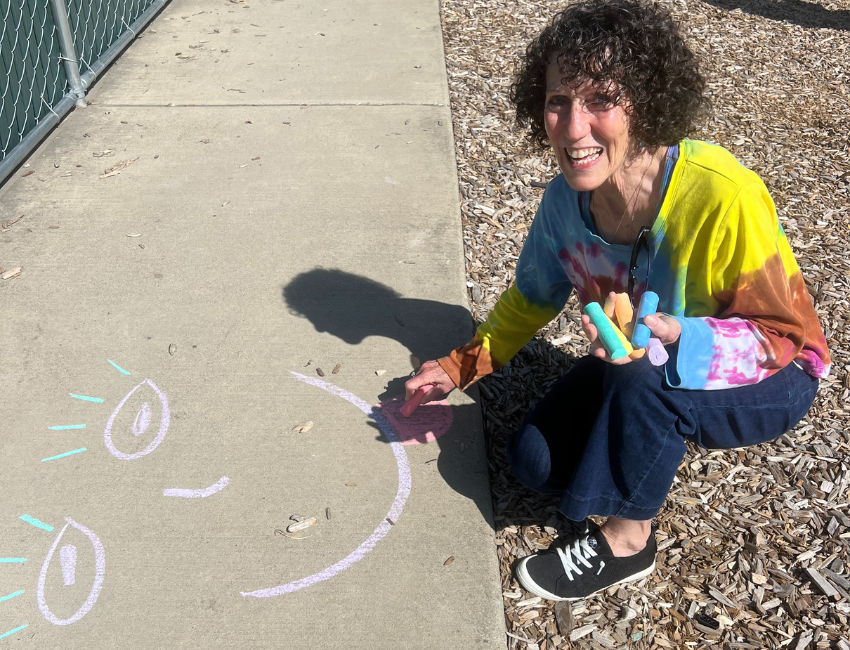 Cheryl Smiling and drawing smiley faces with sidewalk chalk